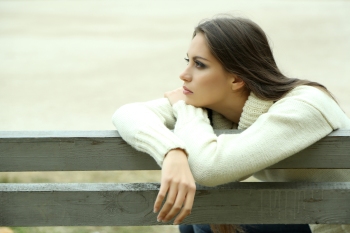 Young lonely woman on bench in park